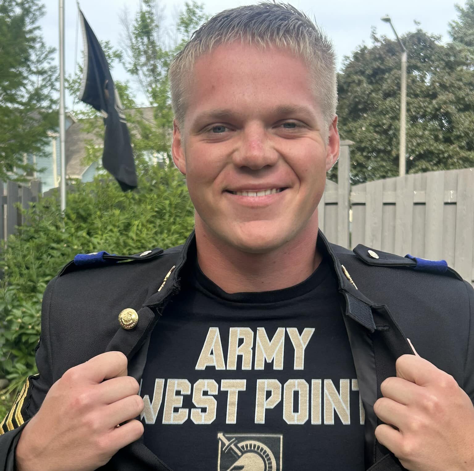 male cadet showing off his west point army shirt underneath his class A uniform jacket smiling